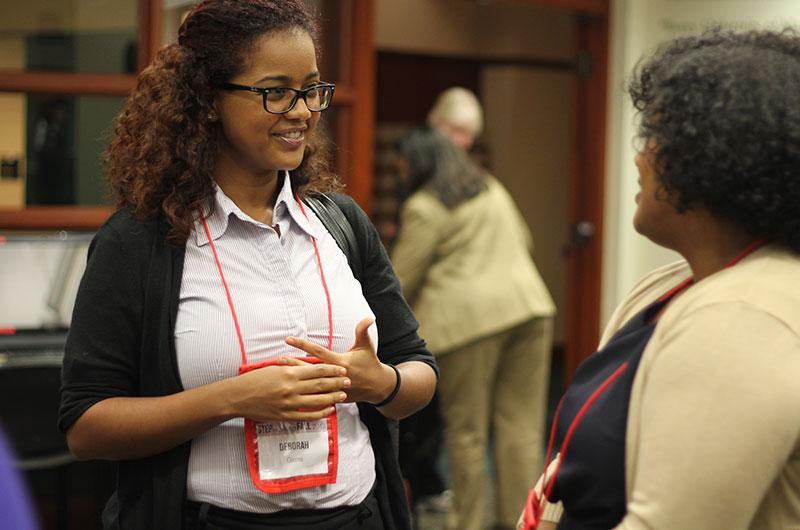 Woman in glasses smiling and talking to another woman